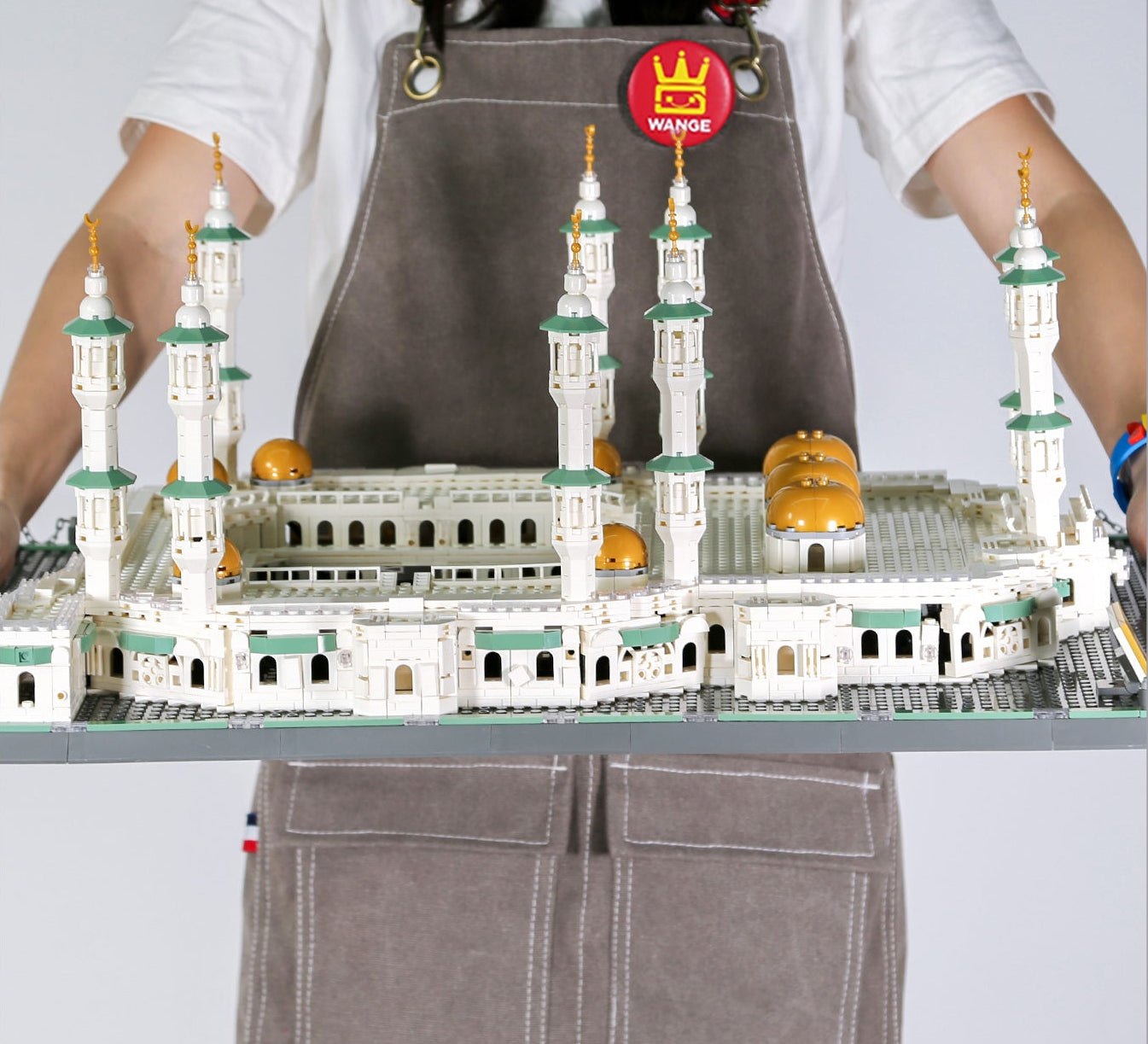 Person wearing an apron with a model of a mosque on a table